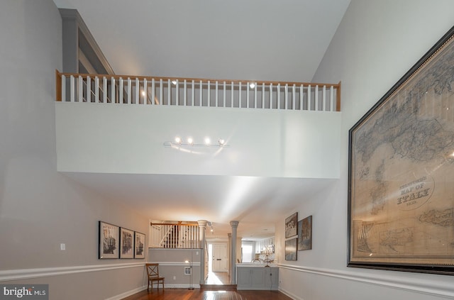 interior space featuring ornate columns, hardwood / wood-style floors, and a towering ceiling