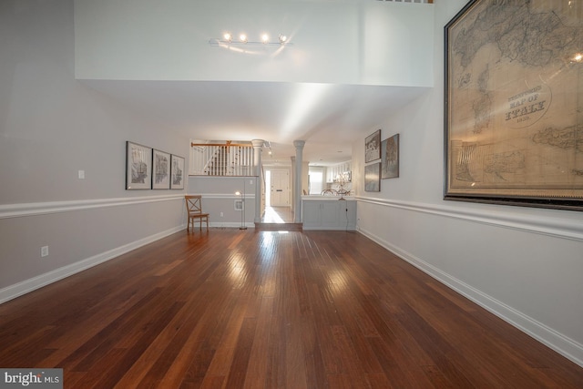 unfurnished living room featuring wood-type flooring and ornate columns