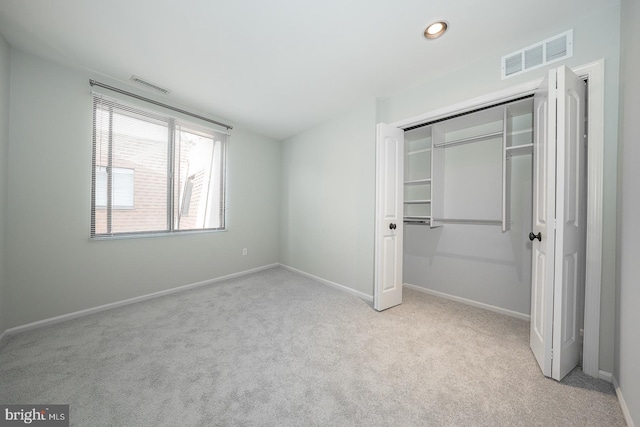 unfurnished bedroom with light colored carpet and a closet