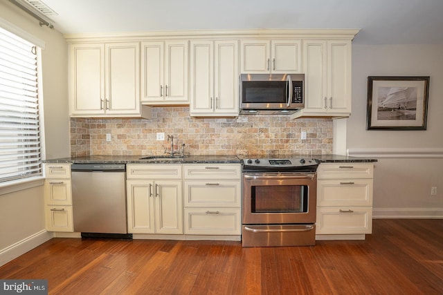 kitchen featuring cream cabinetry, dark hardwood / wood-style flooring, backsplash, and appliances with stainless steel finishes