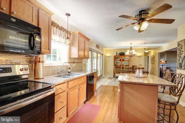 kitchen with decorative backsplash, light wood-type flooring, sink, black appliances, and pendant lighting