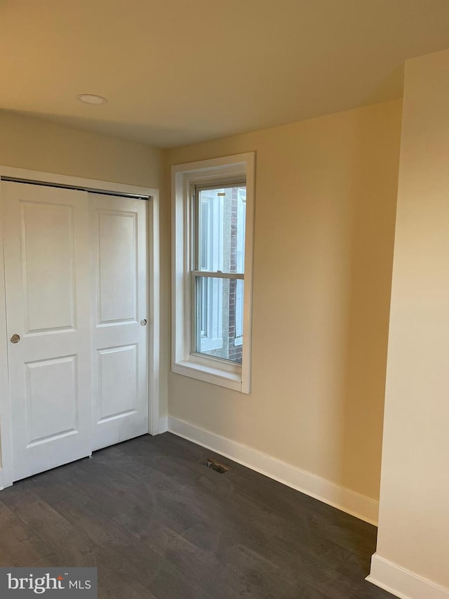 unfurnished bedroom with a closet and dark wood-type flooring