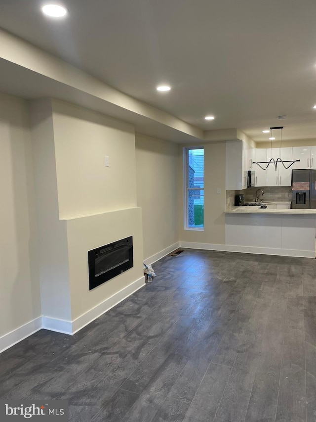 unfurnished living room with dark hardwood / wood-style floors and sink