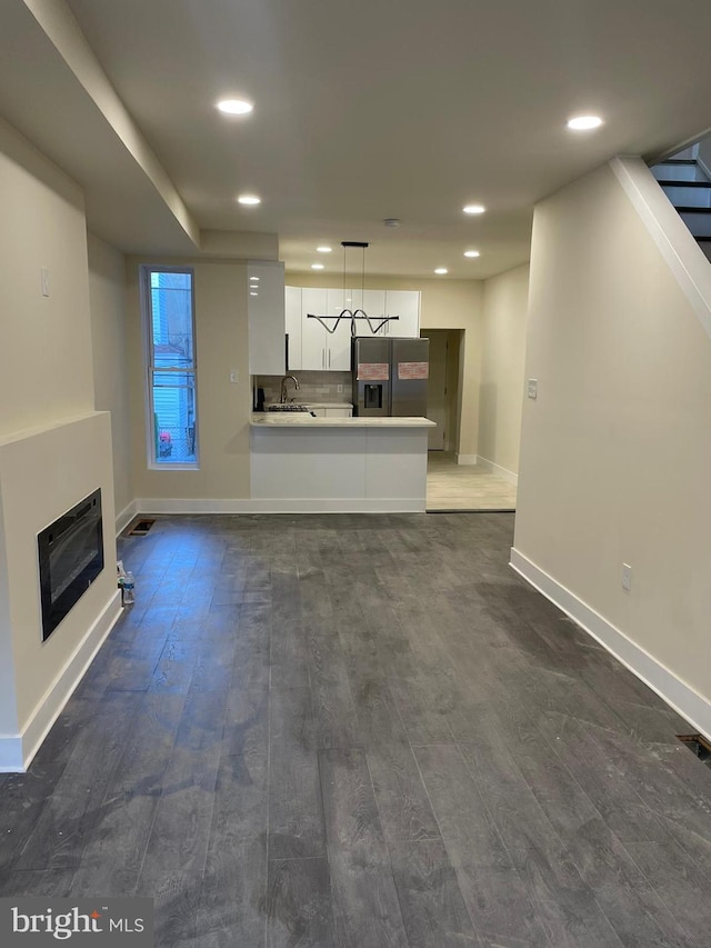 unfurnished living room featuring sink and dark hardwood / wood-style flooring