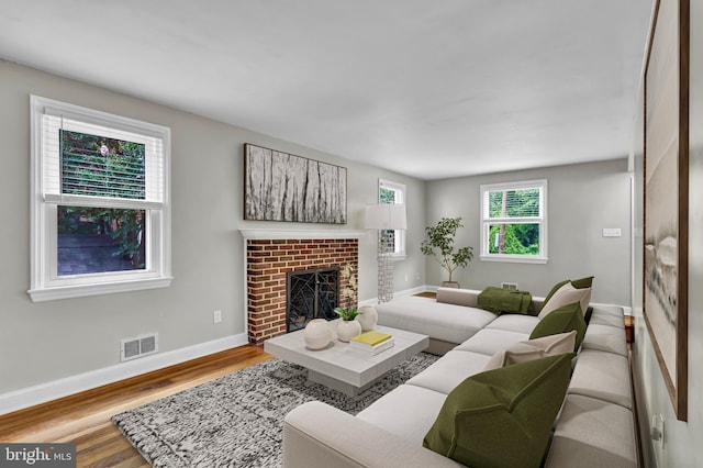 living room with hardwood / wood-style flooring and a brick fireplace