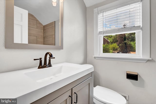 bathroom with vanity, toilet, and lofted ceiling