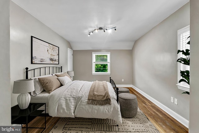 bedroom with hardwood / wood-style floors, vaulted ceiling, and multiple windows