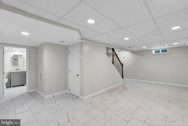 basement featuring a drop ceiling and sink