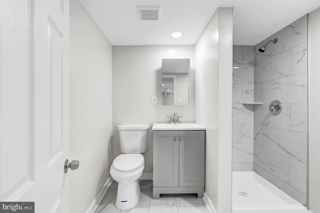 bathroom with toilet, a tile shower, and vanity