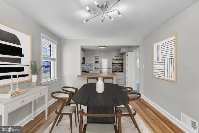 dining area featuring a notable chandelier and light wood-type flooring