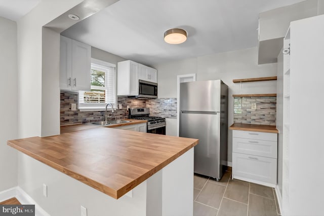 kitchen featuring wood counters, kitchen peninsula, stainless steel appliances, and white cabinets