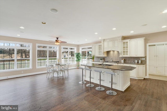 kitchen with backsplash, dark hardwood / wood-style floors, a breakfast bar area, and a kitchen island with sink