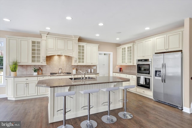 kitchen featuring sink, dark hardwood / wood-style flooring, an island with sink, a breakfast bar area, and appliances with stainless steel finishes