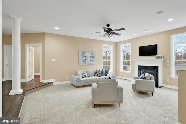 living room with wood-type flooring, decorative columns, and ceiling fan