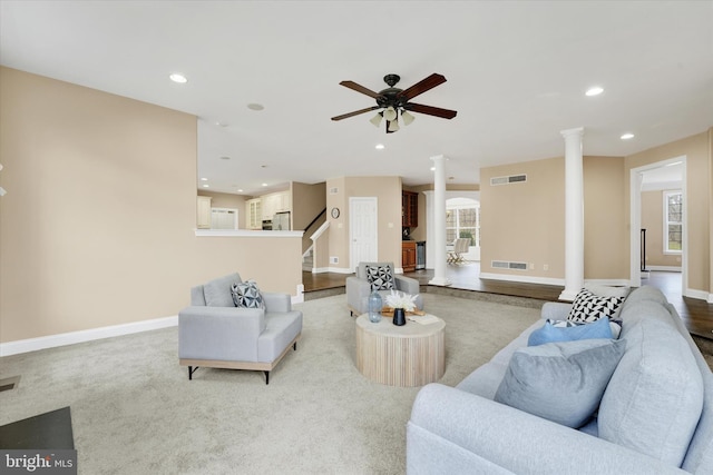 living room featuring ceiling fan, light colored carpet, and ornate columns