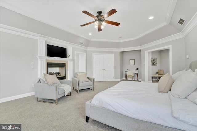 carpeted bedroom with ceiling fan, a multi sided fireplace, ornamental molding, and a closet