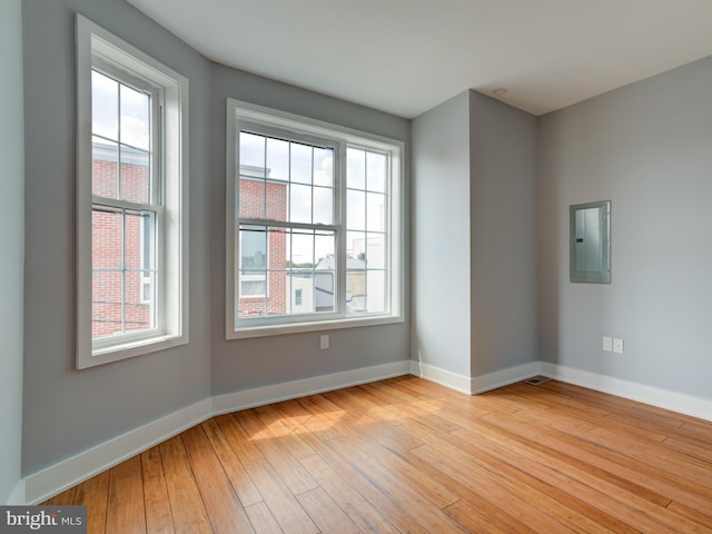 unfurnished room featuring electric panel and light hardwood / wood-style flooring