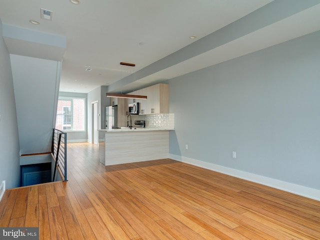 unfurnished living room featuring light hardwood / wood-style floors and sink