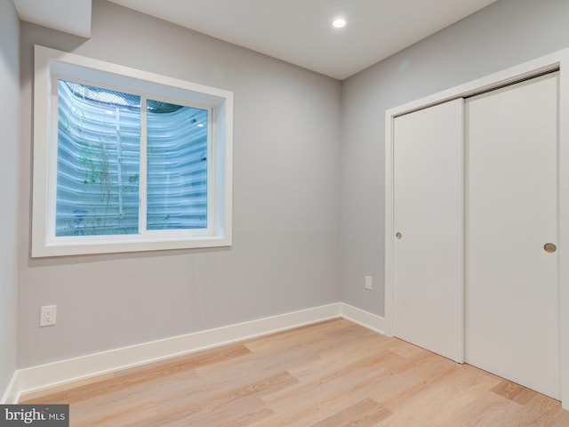 unfurnished bedroom with light hardwood / wood-style flooring and a closet