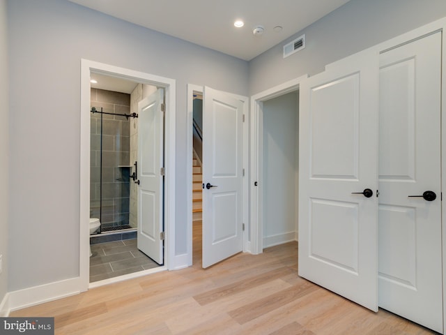 unfurnished bedroom featuring connected bathroom and light hardwood / wood-style flooring