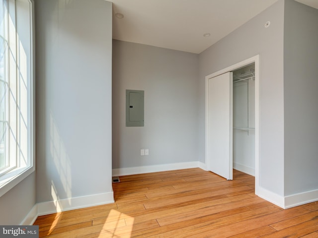 unfurnished bedroom featuring electric panel, light hardwood / wood-style flooring, and a closet