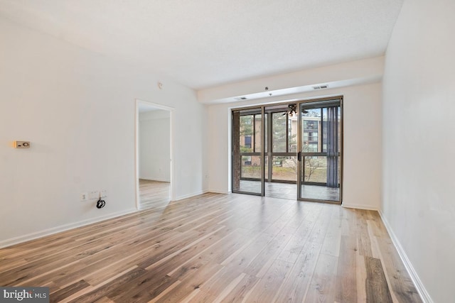 spare room featuring light wood-type flooring, baseboards, and visible vents