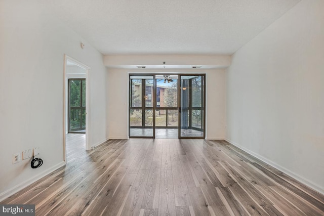 spare room featuring a textured ceiling, wood finished floors, and baseboards