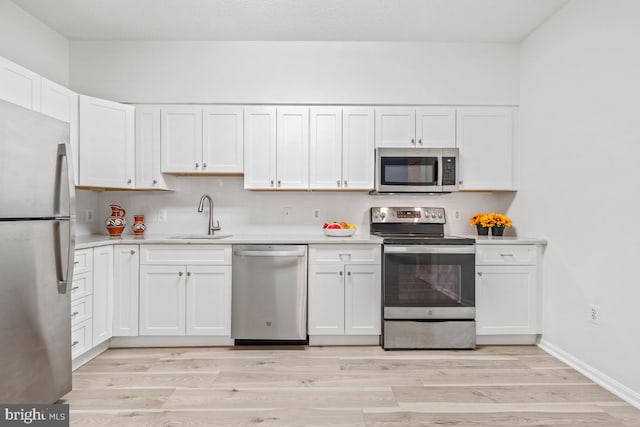 kitchen featuring stainless steel appliances, light countertops, a sink, and white cabinetry