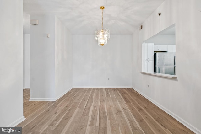 empty room featuring baseboards, light wood-type flooring, visible vents, and an inviting chandelier