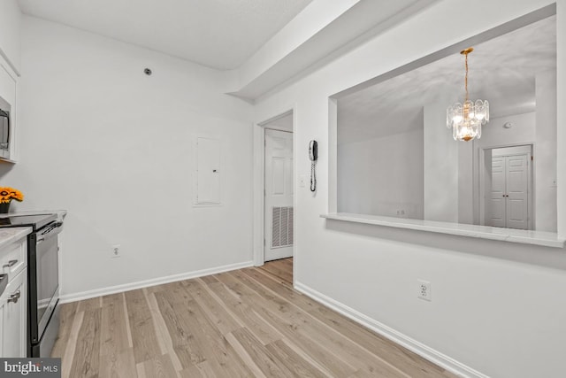 kitchen featuring light countertops, light wood-type flooring, stainless steel range with electric cooktop, and baseboards