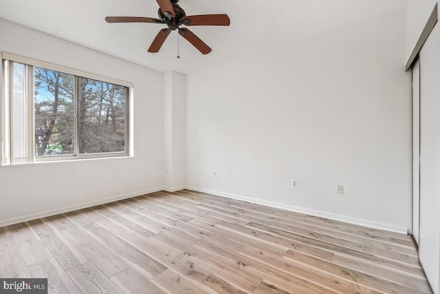 unfurnished bedroom featuring light wood-type flooring, a ceiling fan, baseboards, and a closet