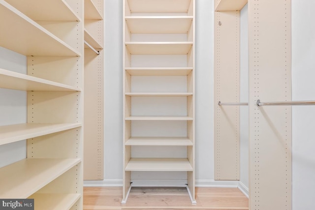 walk in closet with wood finished floors