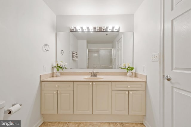 bathroom with toilet, a stall shower, baseboards, and vanity