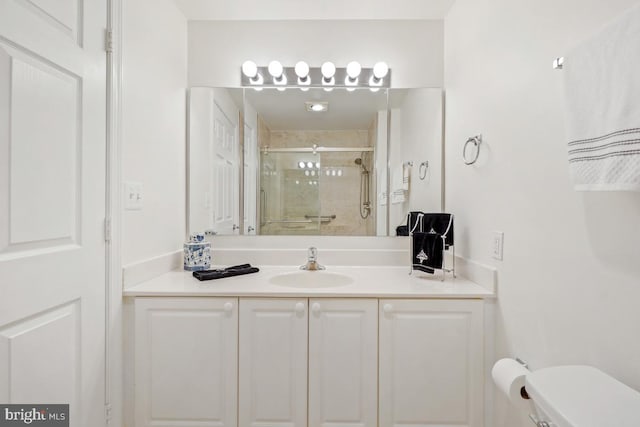 bathroom featuring toilet, a shower stall, and vanity