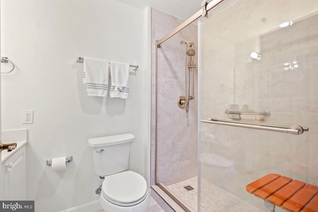 bathroom featuring vanity, a shower stall, toilet, and baseboards