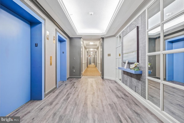 hall with elevator, crown molding, baseboards, and wood finished floors