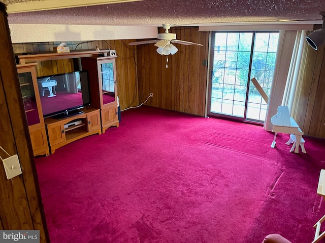 carpeted living room with ceiling fan and wooden walls