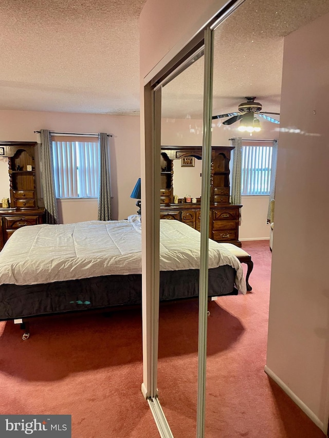 bedroom with ceiling fan, carpet, and a textured ceiling