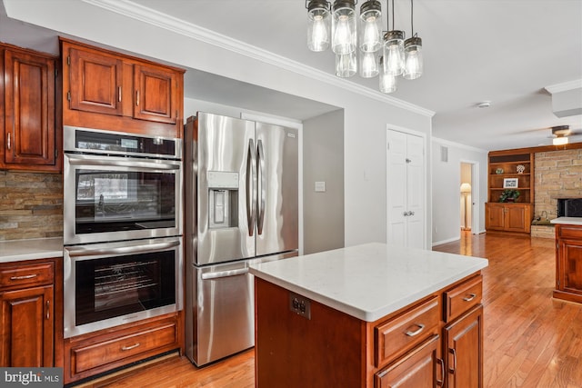 kitchen with pendant lighting, appliances with stainless steel finishes, a kitchen island, light hardwood / wood-style floors, and built in features