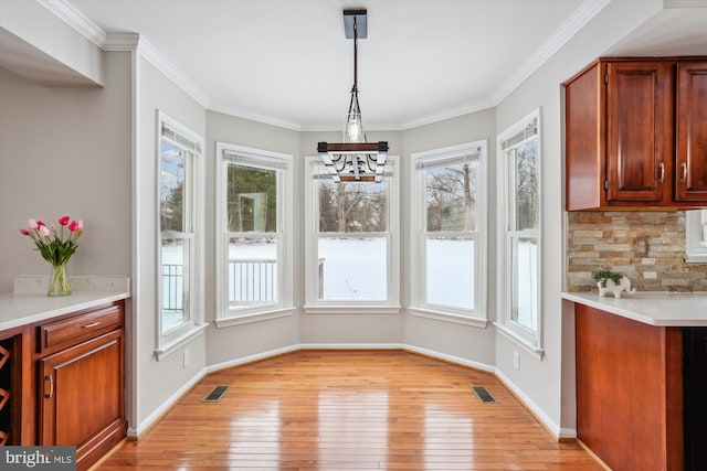 unfurnished dining area with crown molding and light wood-type flooring