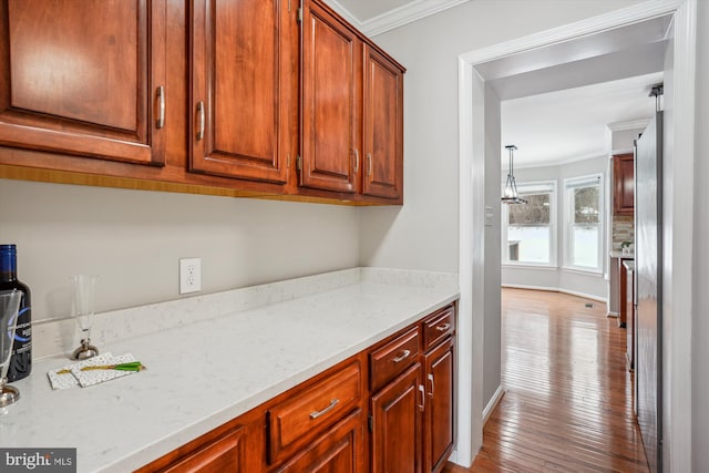 interior space with decorative light fixtures, light stone counters, ornamental molding, and light hardwood / wood-style flooring