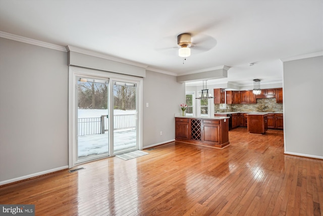 kitchen with decorative light fixtures, light hardwood / wood-style flooring, ornamental molding, and tasteful backsplash