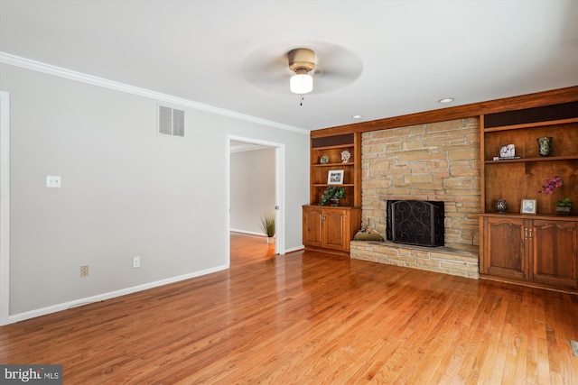 unfurnished living room featuring a stone fireplace, ceiling fan, light wood-type flooring, built in features, and ornamental molding