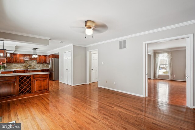 unfurnished living room featuring ceiling fan, sink, ornamental molding, and light wood-type flooring