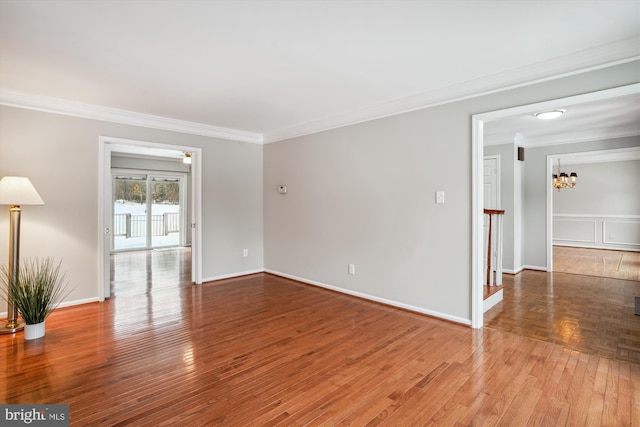 empty room with an inviting chandelier, ornamental molding, and hardwood / wood-style flooring