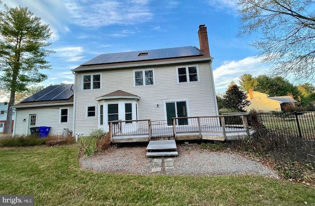 back of property featuring a lawn, solar panels, and a wooden deck