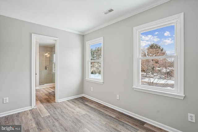 spare room with light wood-type flooring, a wealth of natural light, and ornamental molding