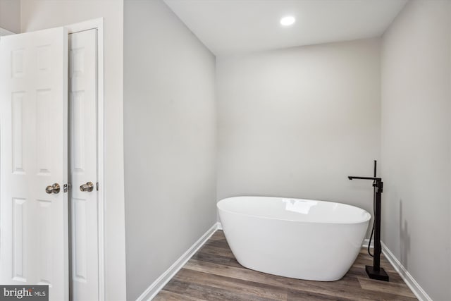 bathroom with a washtub and hardwood / wood-style flooring