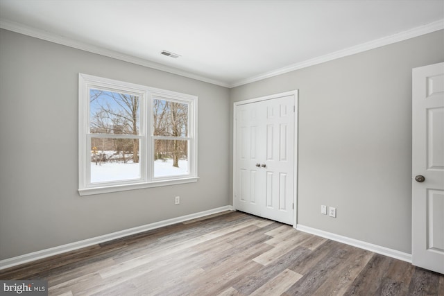 unfurnished bedroom with a closet, crown molding, and hardwood / wood-style flooring