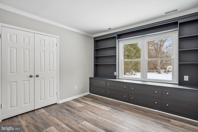 unfurnished bedroom featuring wood-type flooring, a closet, and ornamental molding